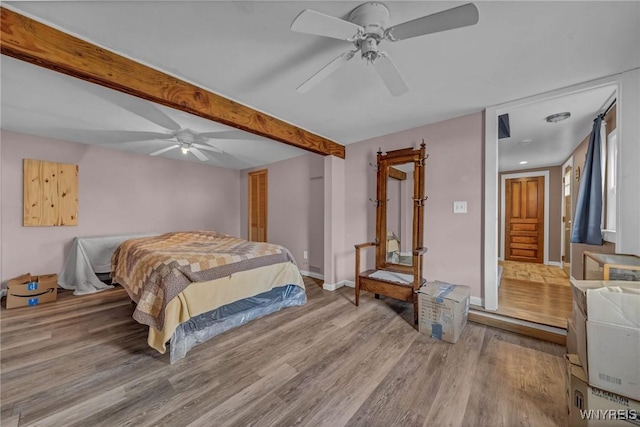 bedroom with beamed ceiling, ceiling fan, baseboards, and wood finished floors