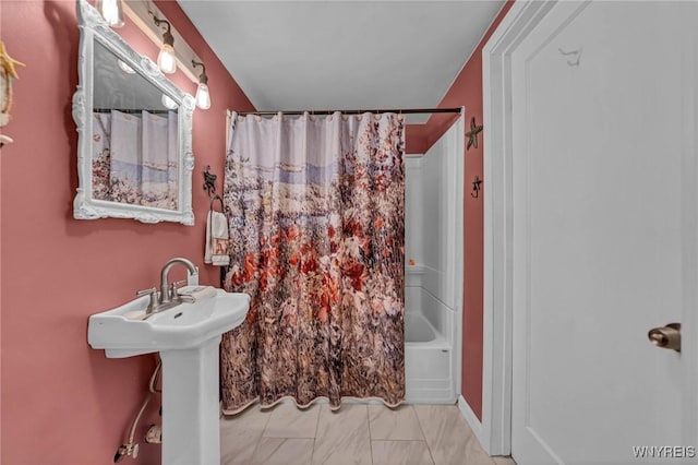 bathroom featuring marble finish floor, shower / bath combo with shower curtain, and a sink