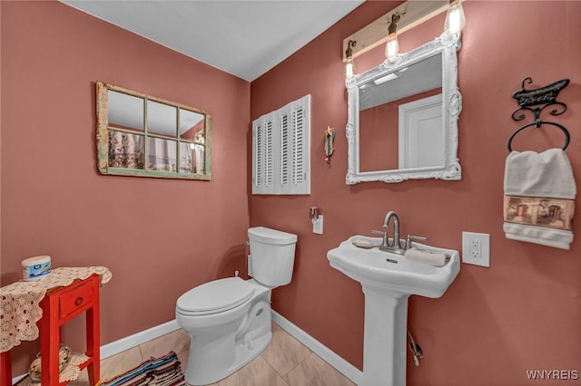 bathroom with tile patterned flooring, toilet, baseboards, and a sink