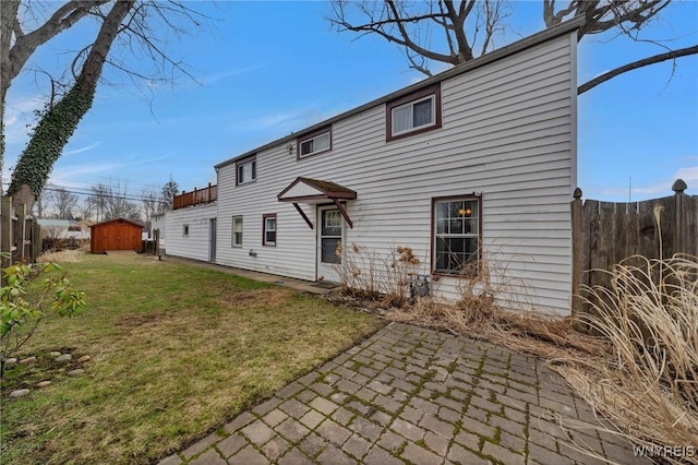 back of house with a storage unit, a patio, a lawn, and an outdoor structure