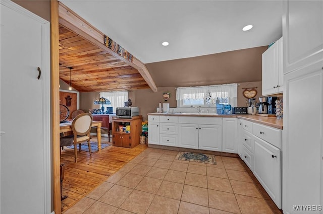 kitchen featuring a sink, stainless steel microwave, plenty of natural light, and white cabinetry