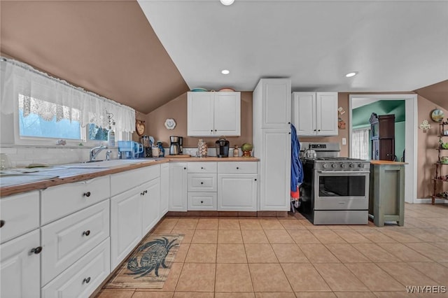 kitchen featuring gas stove, white cabinetry, light tile patterned flooring, and a sink