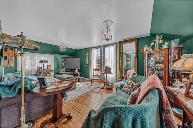 living area featuring an inviting chandelier, wood finished floors, and vaulted ceiling