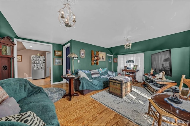 living room with baseboards, an inviting chandelier, wood finished floors, and vaulted ceiling