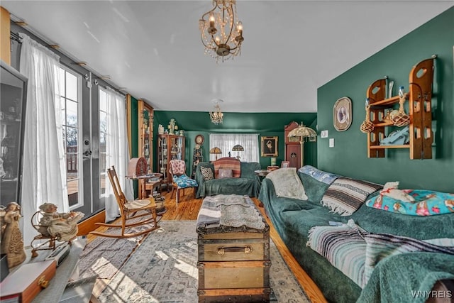 living room featuring an inviting chandelier, wood finished floors, a healthy amount of sunlight, and french doors