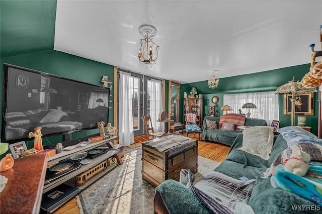 living area featuring wood finished floors, a chandelier, and vaulted ceiling