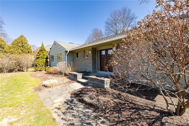 view of front of home featuring a front lawn and stone siding