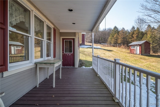 deck with a storage unit, an outbuilding, and covered porch