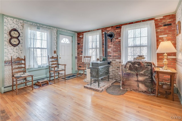 foyer entrance featuring hardwood / wood-style flooring, a wood stove, a wealth of natural light, and a baseboard radiator