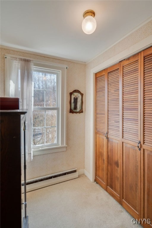 unfurnished bedroom with a baseboard heating unit, a closet, and light carpet