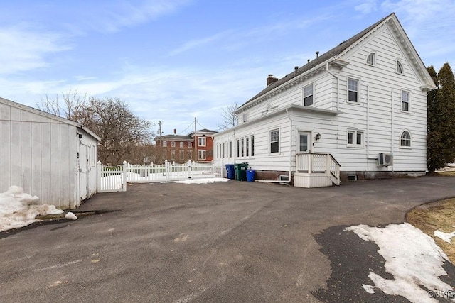 rear view of house featuring a chimney and fence