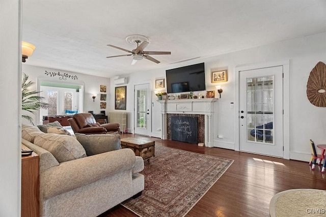 living area featuring a fireplace, wood finished floors, and a ceiling fan