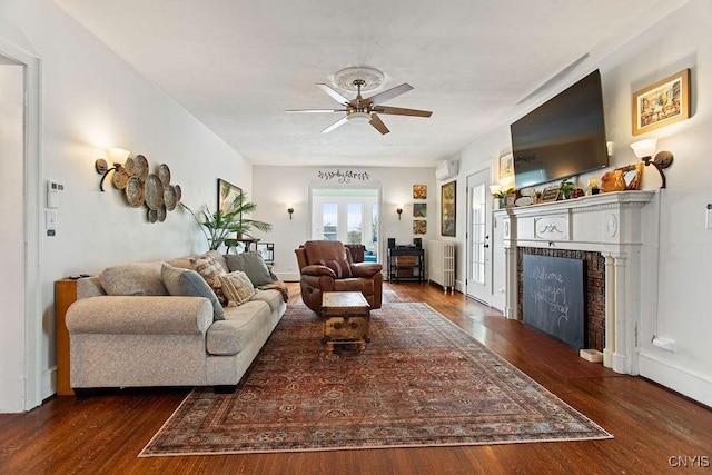 living area with a ceiling fan, wood finished floors, and a fireplace