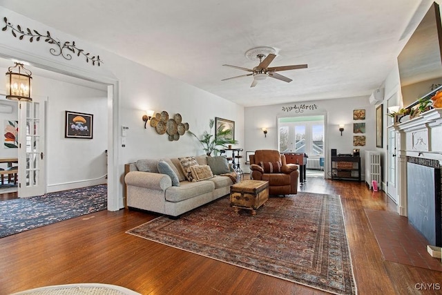 living area featuring a ceiling fan, wood finished floors, and a fireplace