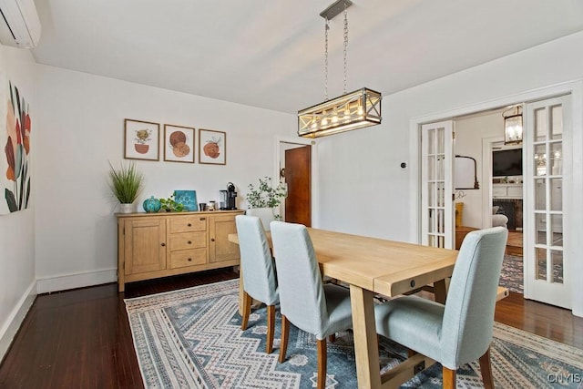 dining area with french doors, dark wood-style flooring, a wall mounted air conditioner, and a chandelier