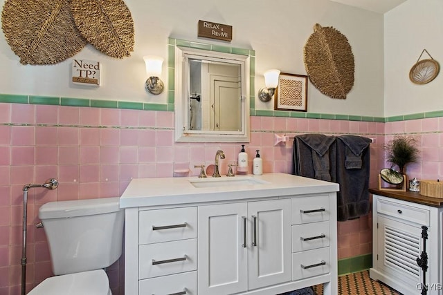 bathroom with wainscoting, vanity, toilet, and tile walls