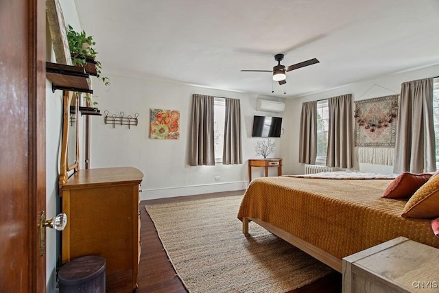 bedroom with a wall mounted air conditioner, baseboards, wood finished floors, and ceiling fan