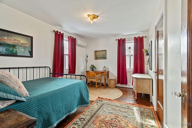 bedroom with an AC wall unit and wood finished floors