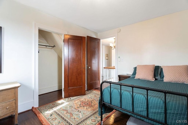 bedroom with a chandelier, baseboards, and wood finished floors