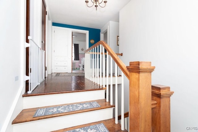 stairs with an inviting chandelier and wood finished floors