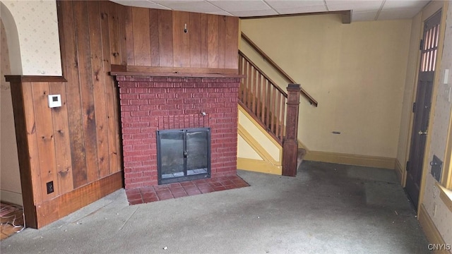 living room featuring a drop ceiling, stairway, arched walkways, wooden walls, and a fireplace