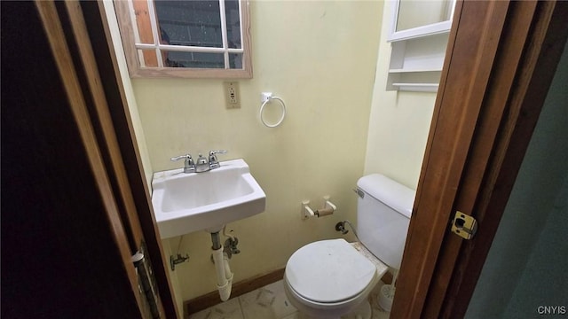 bathroom featuring toilet, baseboards, and a sink