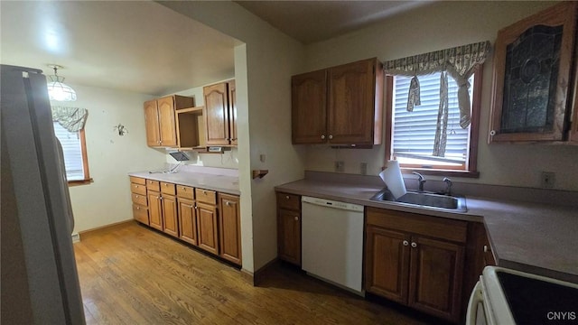 kitchen with white appliances, baseboards, a sink, light wood-style floors, and brown cabinets