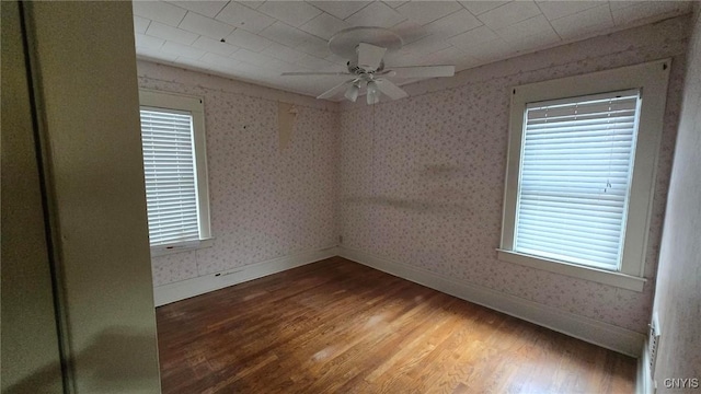 empty room with ceiling fan, baseboards, wood finished floors, and wallpapered walls