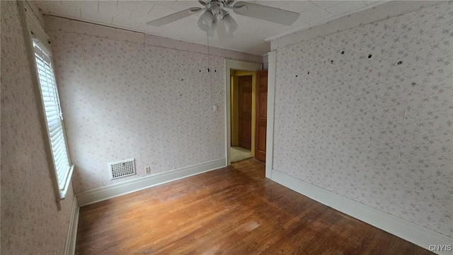 spare room with visible vents, wallpapered walls, baseboards, wood finished floors, and a ceiling fan