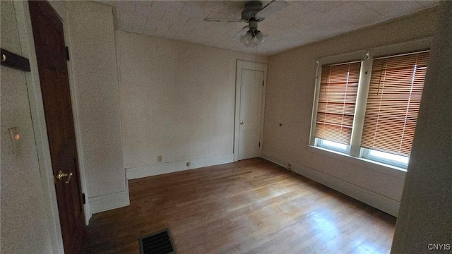 unfurnished room featuring ceiling fan, visible vents, baseboards, and wood finished floors