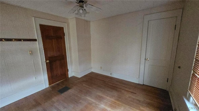 spare room featuring baseboards, wood finished floors, visible vents, and ceiling fan