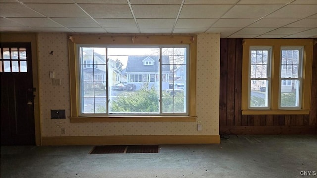 foyer with a wealth of natural light, visible vents, wallpapered walls, and carpet floors