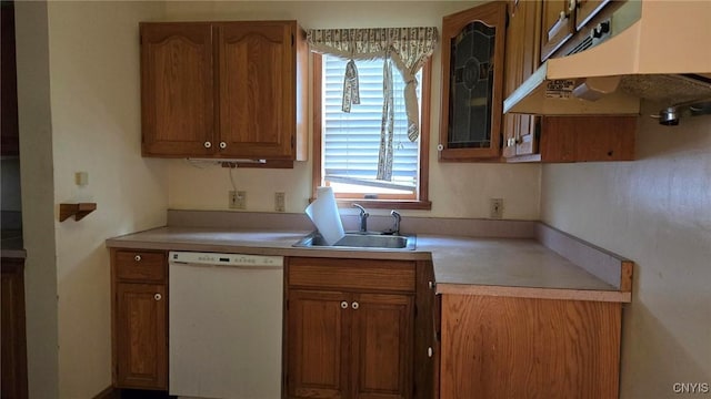 kitchen with under cabinet range hood, dishwasher, light countertops, brown cabinets, and a sink