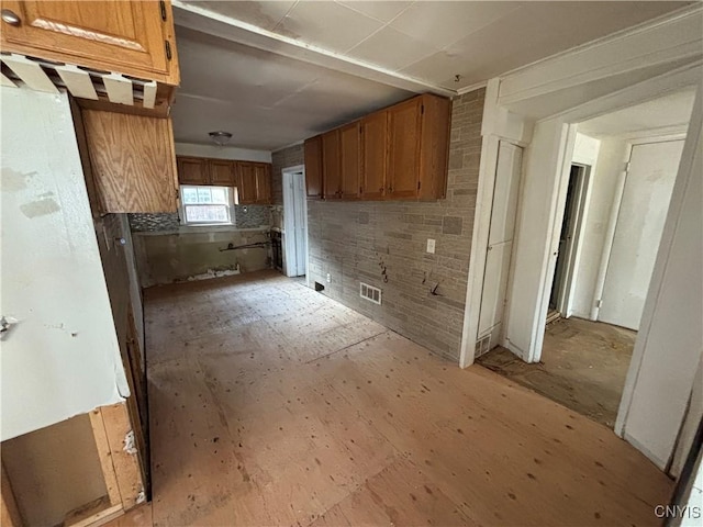 kitchen with brown cabinetry and brick wall