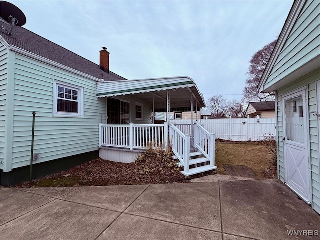 exterior space with a porch, a chimney, and fence