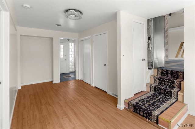 foyer featuring baseboards, wood finished floors, and stairs