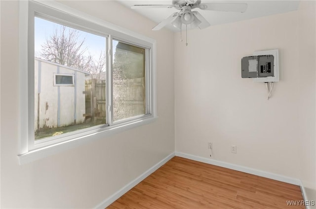 spare room with a wealth of natural light, light wood-style flooring, baseboards, and ceiling fan