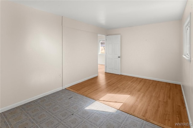 spare room featuring baseboards and wood finished floors