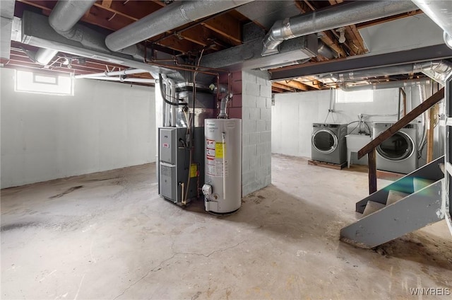 basement featuring gas water heater, heating unit, and independent washer and dryer