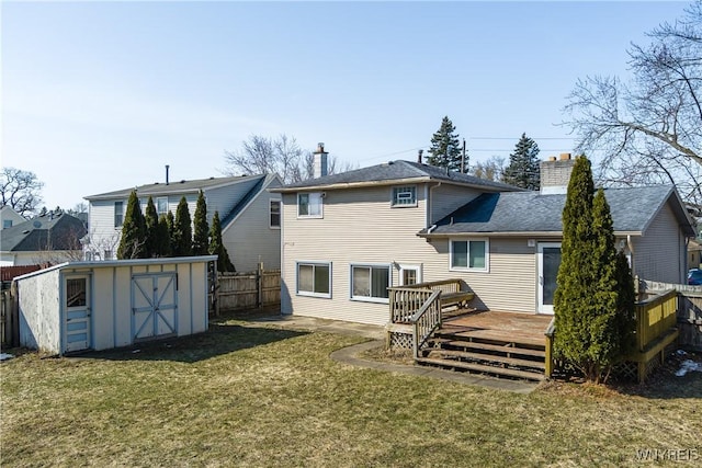 back of house featuring a storage unit, an outbuilding, a lawn, fence, and a chimney