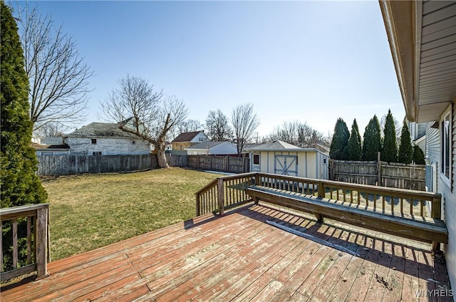 deck featuring a yard, an outbuilding, a fenced backyard, and a shed