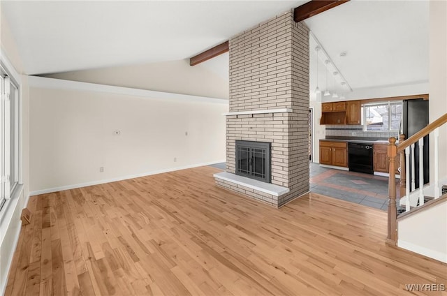 unfurnished living room with beam ceiling, a fireplace, baseboards, and light wood-style floors