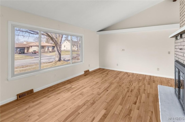 unfurnished living room with visible vents, baseboards, lofted ceiling, light wood-style flooring, and a fireplace