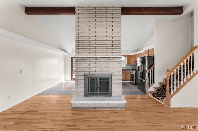 unfurnished living room with baseboards, beamed ceiling, stairway, light wood-style flooring, and a fireplace