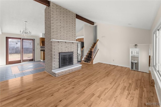 unfurnished living room with light wood finished floors, high vaulted ceiling, an inviting chandelier, a fireplace, and beamed ceiling