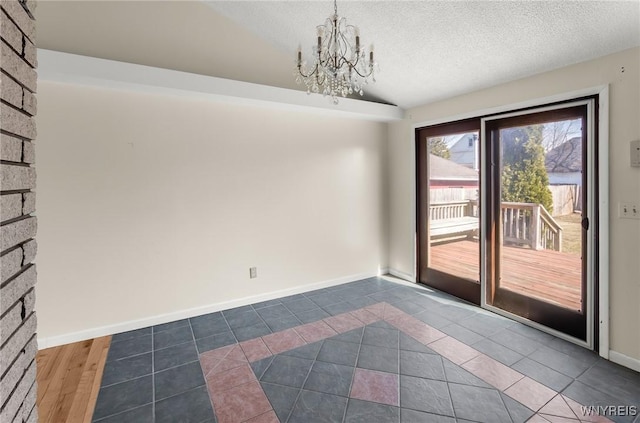 unfurnished room with dark tile patterned floors, lofted ceiling, a textured ceiling, and a chandelier