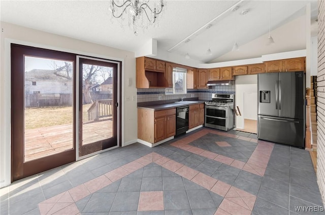 kitchen with lofted ceiling, dark tile patterned flooring, appliances with stainless steel finishes, and a sink