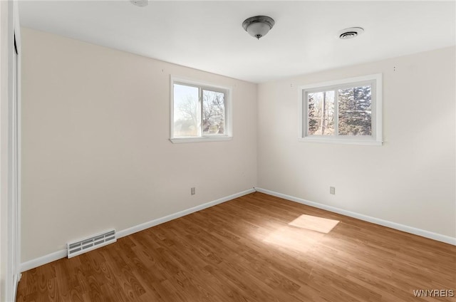 unfurnished room featuring visible vents, baseboards, and wood finished floors