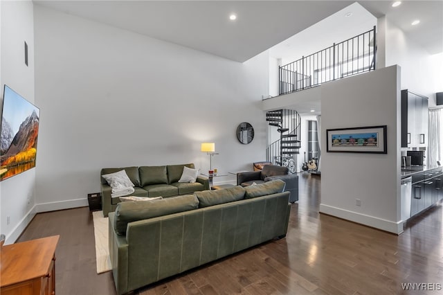 living room with baseboards, dark wood-style floors, a high ceiling, and stairs