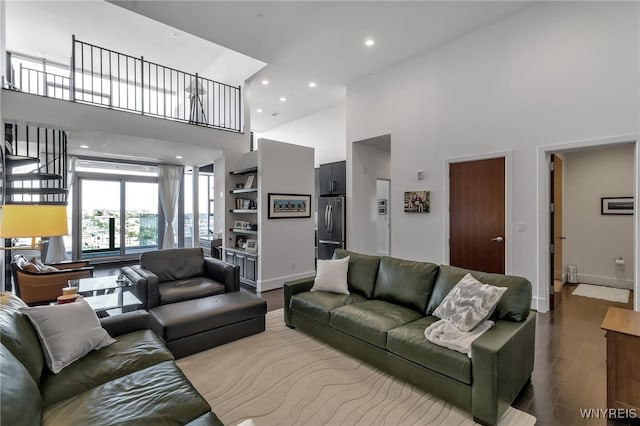 living area featuring recessed lighting, a high ceiling, baseboards, and wood finished floors